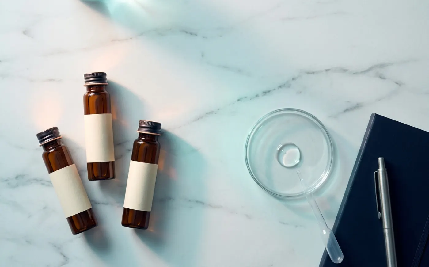 Lab vials and notebook on a marble surface